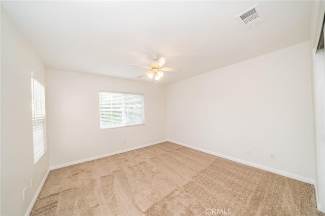 spare room with baseboards, ceiling fan, visible vents, and light colored carpet