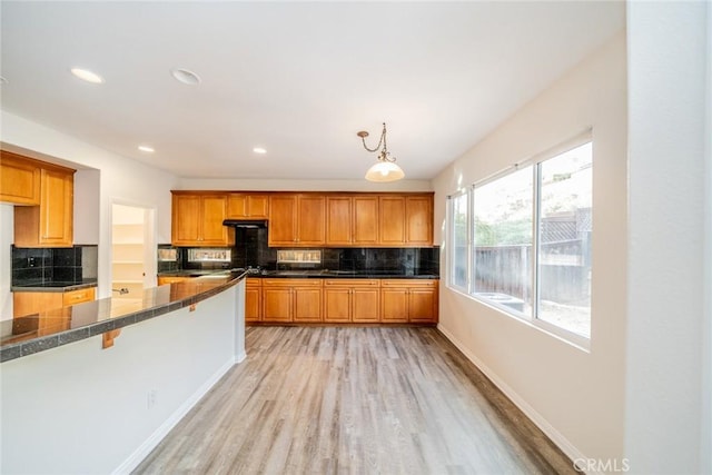 kitchen featuring light wood-type flooring, brown cabinetry, and decorative backsplash