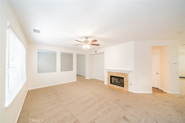 unfurnished living room featuring light colored carpet, a tile fireplace, and ceiling fan