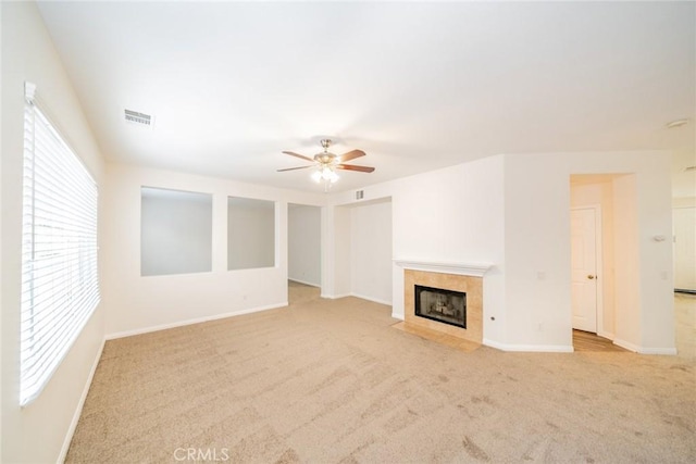 unfurnished living room featuring baseboards, visible vents, a ceiling fan, carpet, and a fireplace