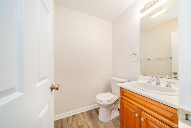 bathroom with wood finished floors, vanity, toilet, and baseboards