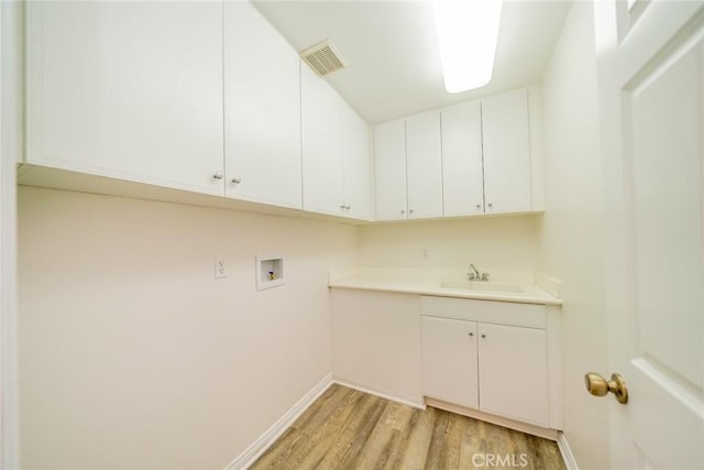 clothes washing area featuring hookup for a washing machine, a sink, visible vents, cabinet space, and light wood finished floors