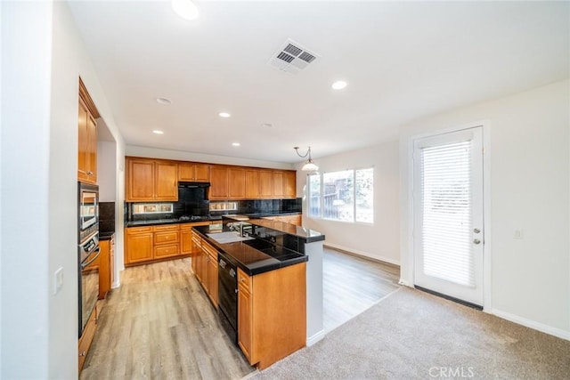 kitchen with visible vents, decorative backsplash, dark countertops, an island with sink, and a sink