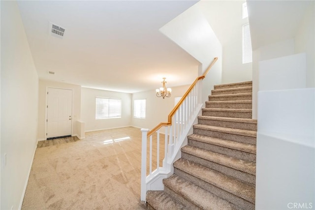 stairway with a chandelier, baseboards, visible vents, and carpet flooring