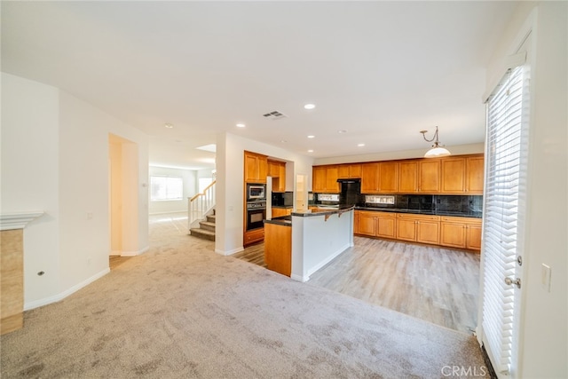 kitchen featuring a center island, light hardwood / wood-style flooring, backsplash, and oven