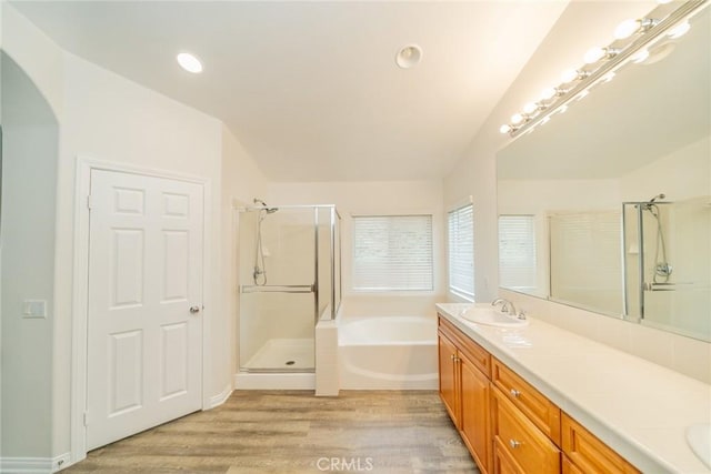 bathroom with a garden tub, a sink, wood finished floors, a shower stall, and double vanity