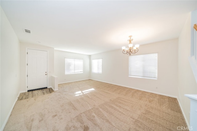 carpeted empty room featuring an inviting chandelier