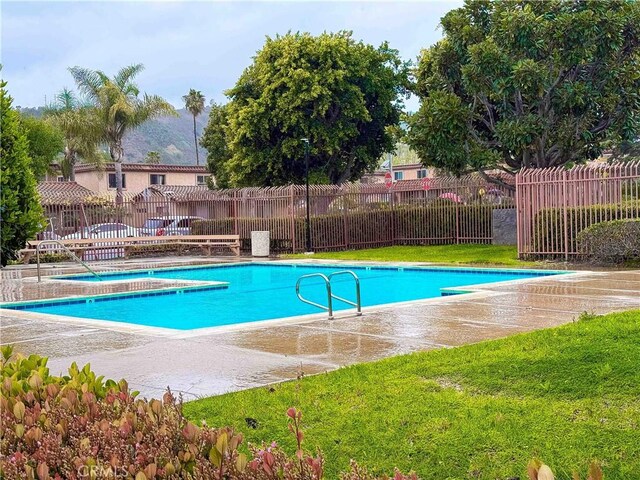 community pool featuring fence and a lawn