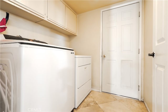 laundry area featuring cabinets, light tile patterned floors, and washer and clothes dryer