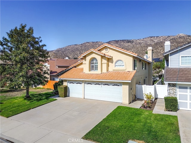 view of front of house featuring a mountain view, a garage, and a front lawn