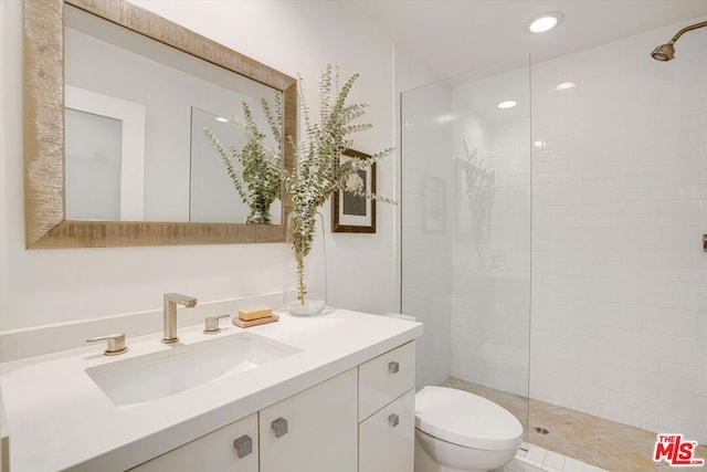 bathroom with tiled shower, vanity, toilet, and tile patterned flooring