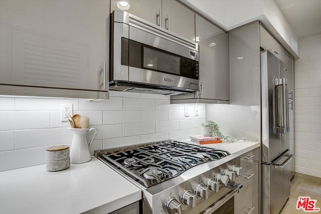 kitchen with tasteful backsplash, gray cabinetry, and stainless steel appliances