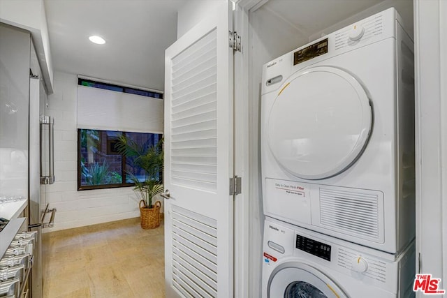 clothes washing area featuring stacked washing maching and dryer and light hardwood / wood-style flooring