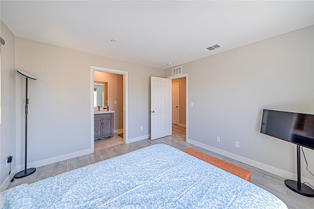 bedroom with light wood-type flooring and connected bathroom