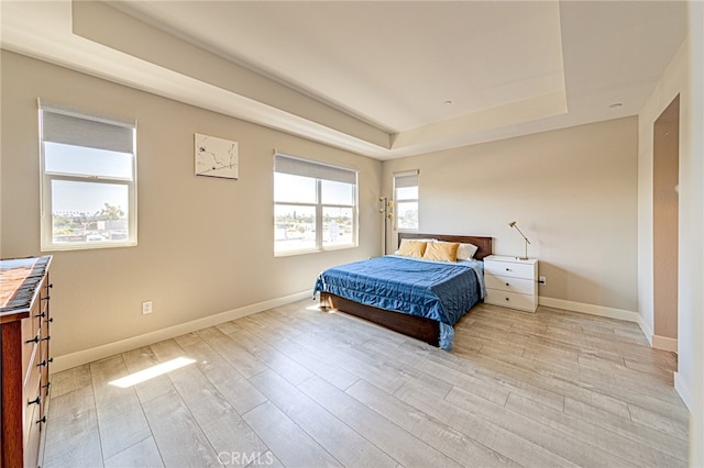 bedroom featuring light hardwood / wood-style flooring and a tray ceiling