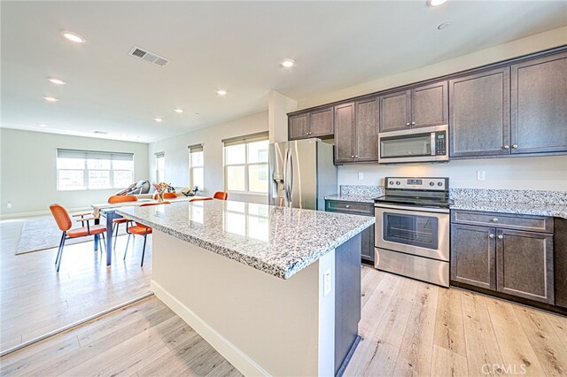 kitchen featuring light hardwood / wood-style floors, a kitchen island, light stone countertops, and stainless steel appliances