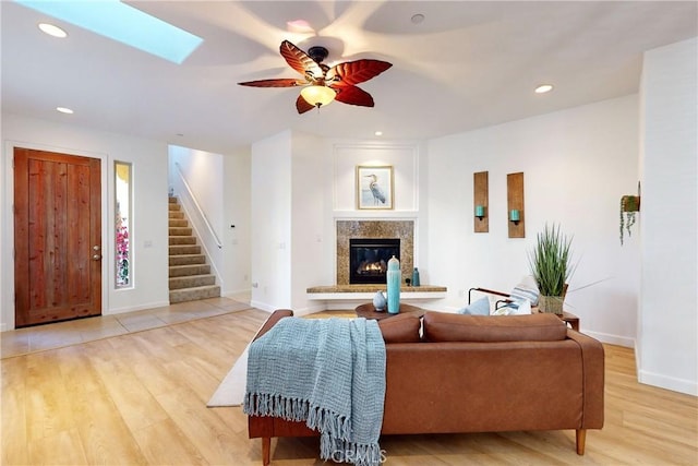 living room featuring ceiling fan, light wood-type flooring, and a skylight