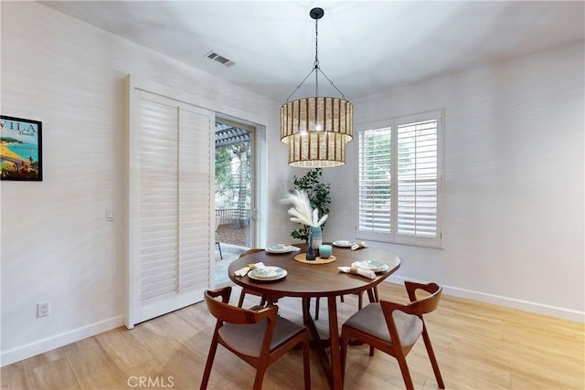 dining space with a notable chandelier and light hardwood / wood-style floors