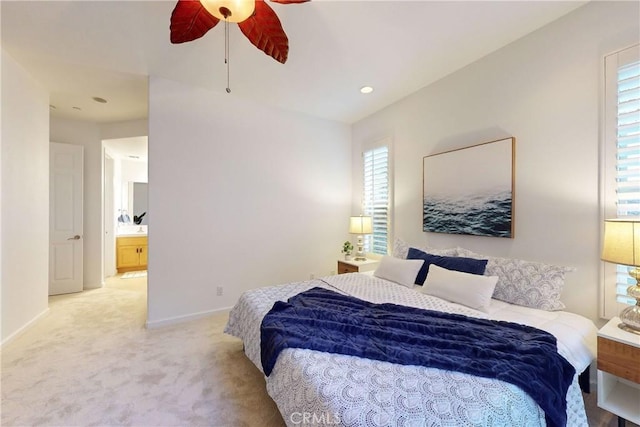 carpeted bedroom with ensuite bath and ceiling fan