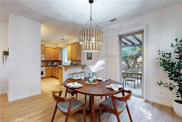 dining area with light wood-type flooring and a chandelier