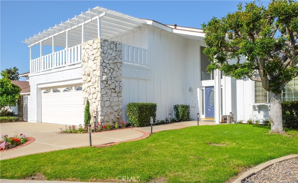 view of front facade featuring a pergola, a garage, and a front lawn