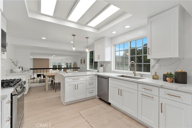 15562 Placid Cir, Huntington Beach, CA 92647 - kitchen with light wood finished floors, a peninsula, a sink, stainless steel appliances, and white cabinetry