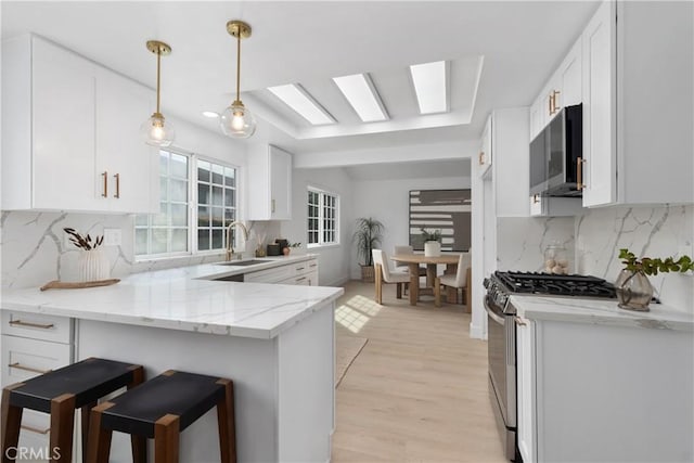 15562 Placid Cir, Huntington Beach, CA 92647 - kitchen featuring light stone countertops, appliances with stainless steel finishes, a peninsula, and white cabinetry