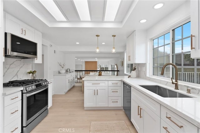 15562 Placid Cir, Huntington Beach, CA 92647 - kitchen featuring light stone counters, a peninsula, a sink, white cabinets, and appliances with stainless steel finishes
