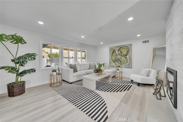 living room with a large fireplace and light hardwood / wood-style flooring