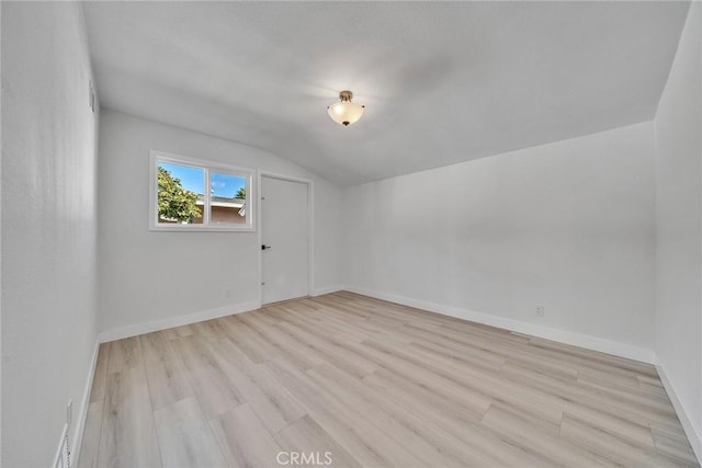 unfurnished room featuring light hardwood / wood-style floors and vaulted ceiling