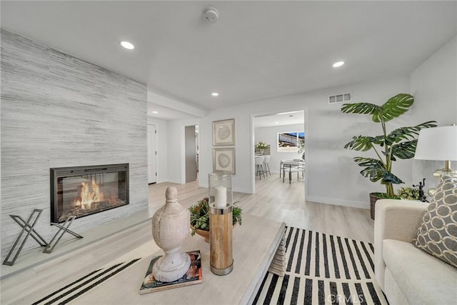 living room with a fireplace, tile walls, and light wood-type flooring