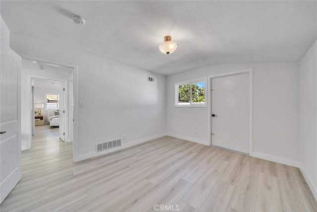 empty room with light hardwood / wood-style floors and lofted ceiling