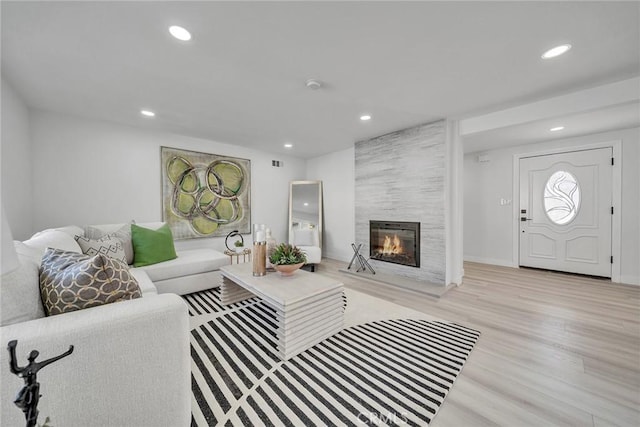 living room featuring a tiled fireplace and light hardwood / wood-style flooring