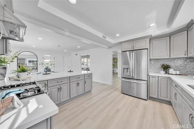 kitchen with gray cabinets, stainless steel fridge, and light hardwood / wood-style flooring