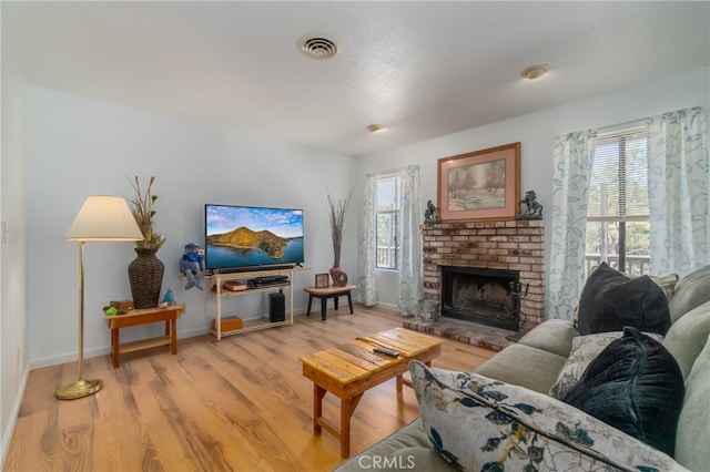 living room featuring light hardwood / wood-style flooring, a fireplace, and a healthy amount of sunlight