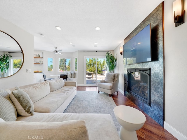 living room with wood-type flooring, a textured ceiling, and ceiling fan