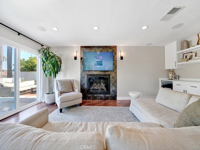 living room with light wood-type flooring, a textured ceiling, and a large fireplace