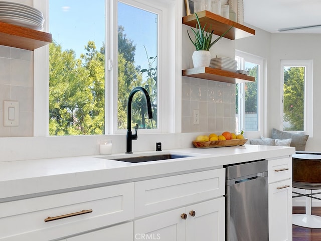 kitchen featuring sink, white cabinets, decorative backsplash, light stone countertops, and stainless steel dishwasher