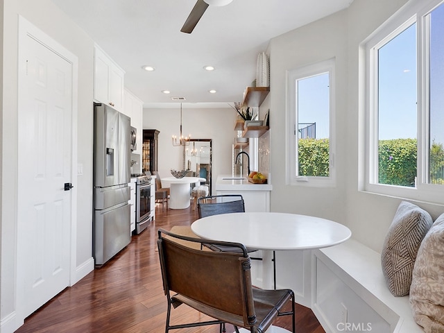 dining room with sink, ceiling fan with notable chandelier, and dark hardwood / wood-style flooring