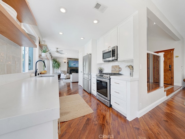 kitchen with dark hardwood / wood-style floors, tasteful backsplash, sink, white cabinets, and stainless steel appliances