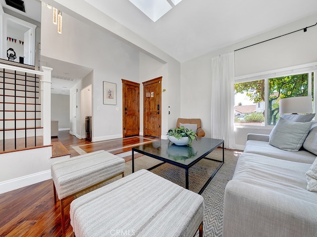 living room with a skylight, hardwood / wood-style flooring, and high vaulted ceiling