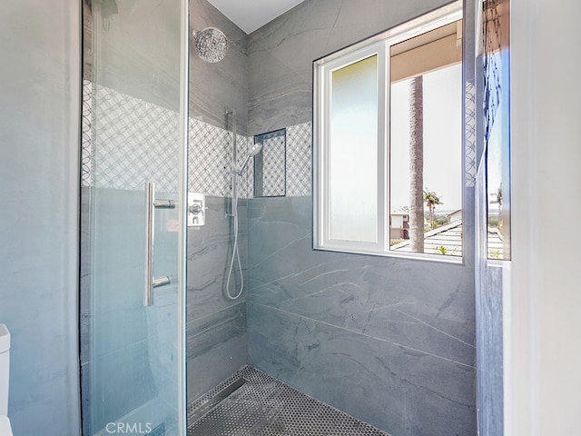 bathroom featuring a shower with door and toilet