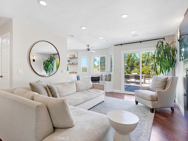 living room with ceiling fan, a textured ceiling, and dark hardwood / wood-style flooring