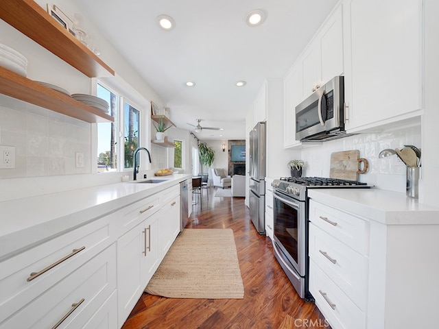 kitchen featuring appliances with stainless steel finishes, tasteful backsplash, white cabinets, dark hardwood / wood-style floors, and sink