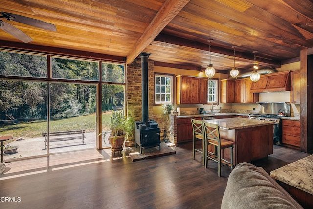 kitchen featuring light stone counters, pendant lighting, a wood stove, high end stainless steel range, and dark hardwood / wood-style flooring