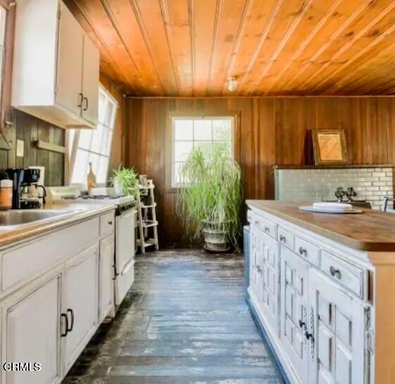 kitchen featuring backsplash, wood walls, dark hardwood / wood-style flooring, and white cabinetry