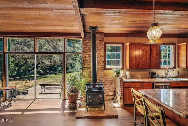 kitchen featuring light stone counters, wood ceiling, a wood stove, decorative light fixtures, and dark hardwood / wood-style floors