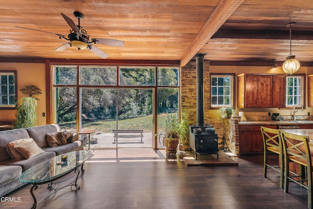 living room with sink, beam ceiling, a wood stove, dark wood-type flooring, and wooden ceiling