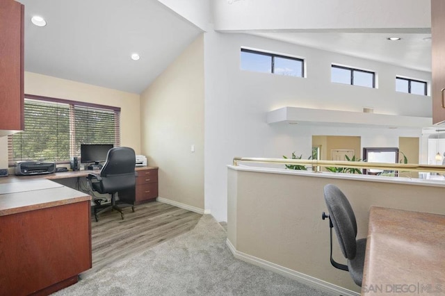 office space with light carpet, a towering ceiling, and a healthy amount of sunlight