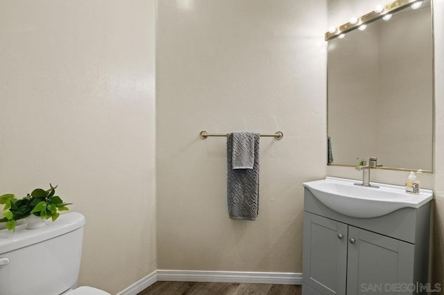 bathroom featuring toilet, hardwood / wood-style flooring, and vanity